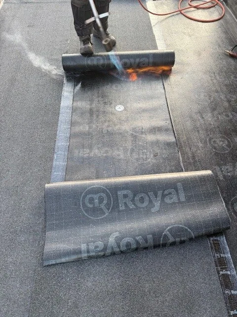 Nieuwe bitumen dakbedekking wordt aangebracht op een plat dak